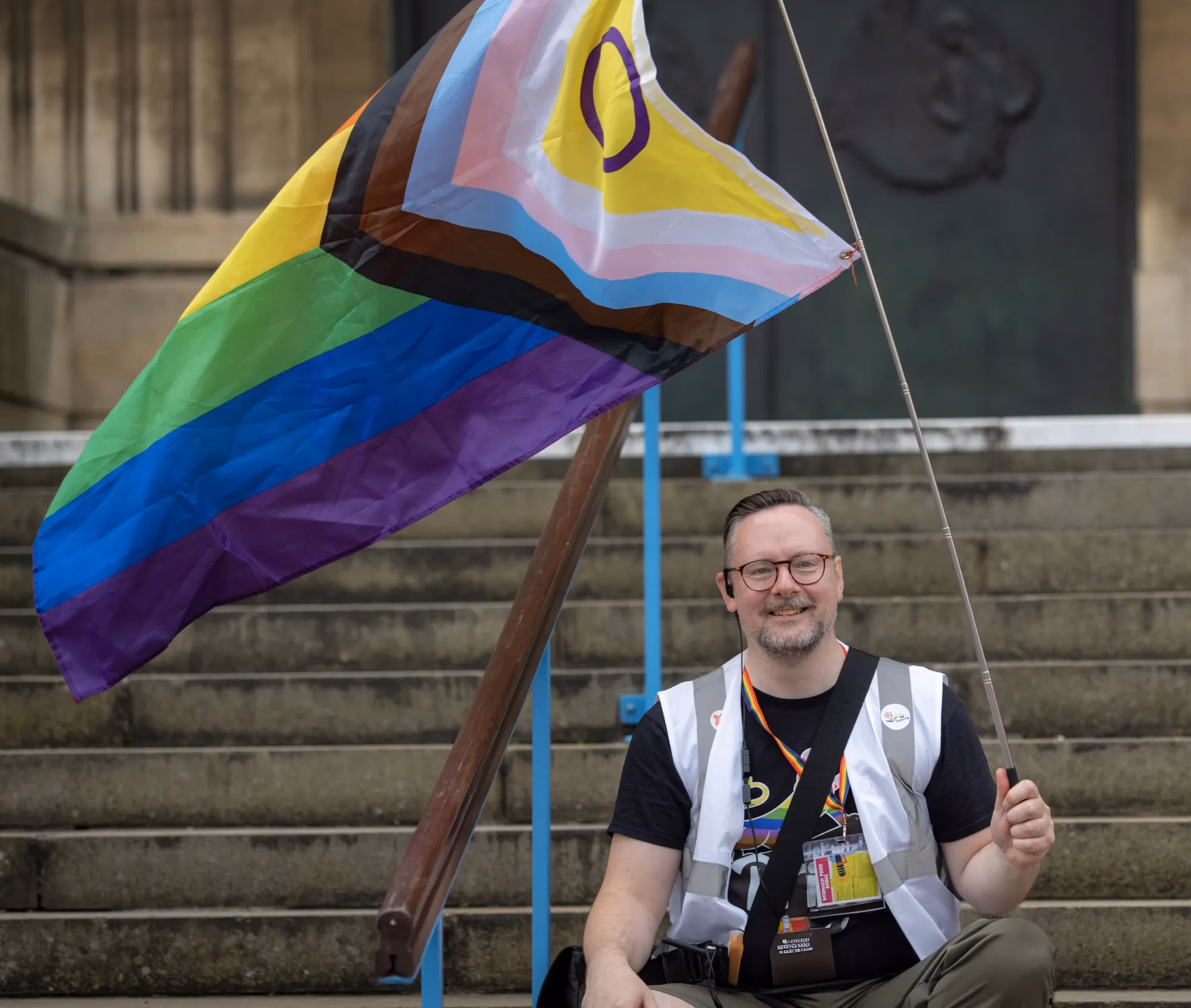 Person sitting on steps, holding pride flag